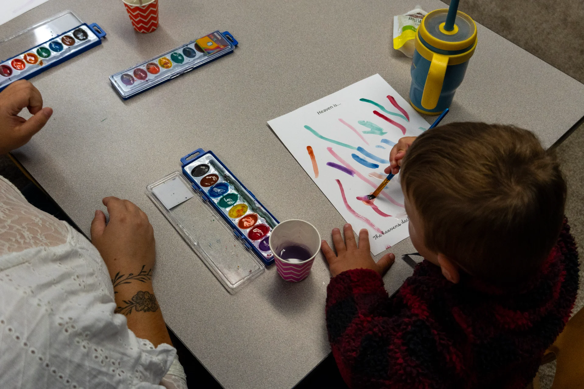 Child painting with an adult helper at GateWay
